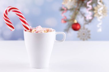 Beyaz bir masada latteli bir bardakta şekerlemeler.