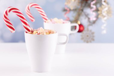 Beyaz bir masada latteli bir bardakta şekerlemeler.