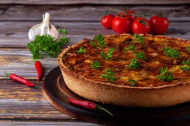 Geleneksel Fransız kiş turtası, ahşap arka planda tavuk ve mantarlı.