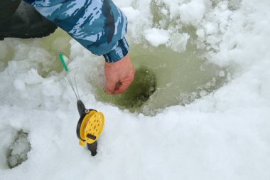 olta kamışı deliğe üzerinde. balıkçı delikten buz temizler