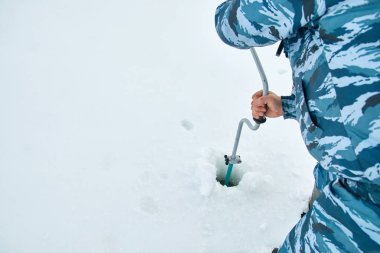Kış Balıkçılık buz üzerinde. Adam buz buz kıracağı ile bir delik matkap.