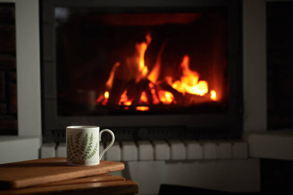 cup of tea. fire in the fireplace. concept of home comfort and warm atmosphere. cozy home