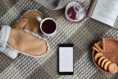 Rahat ev natürmort: çay fincan ve sıcak ekose ile kitap açıldı. Kış tatilleri, Noel zamanı konsepti, akıllı telefon maket