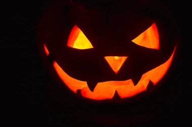 Cadılar Bayramı, koyu bir arka plan üzerinde korkutucu bir Parlak yüz ile turuncu kabak