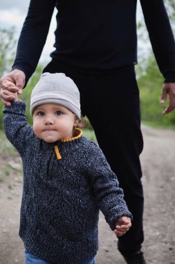 Oğlunun elini tutan güçlü bir baba. Baba ve oğul parkta yürüyorlar.