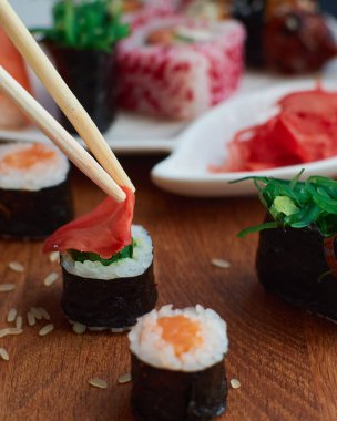 Suşi ruloları. Restoranda Japon yemeği. Bambu çubukları kırmızı zencefili rulo yapar