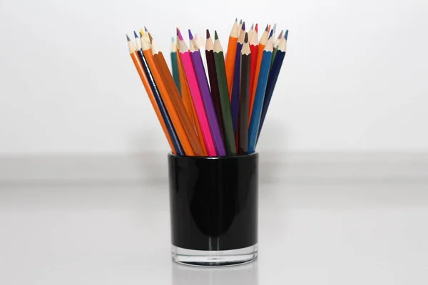 生徒の色鉛筆 鉛筆は 白いテーブルに散在しているし ガラスのスタンドします オフィス ワーカーの鉛筆 — ストック写真