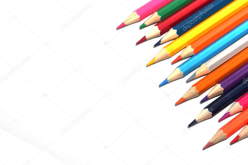 Color pencils for schoolchildren and students. Pencils are scattered on a white table and stand in a glass. Pencils for office workers.
