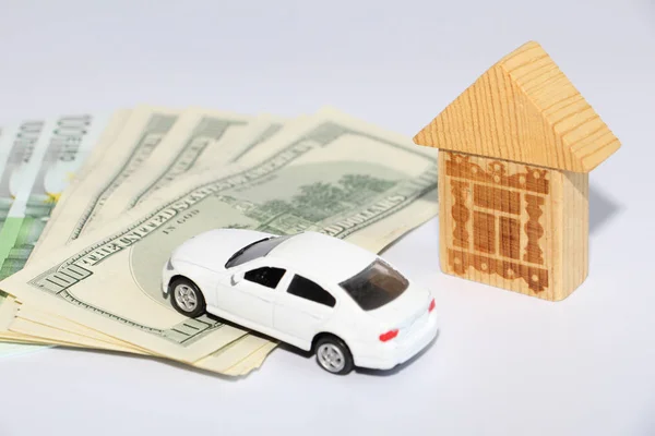 Money on a white background, next to a car and a house. Take the money in the bank. Investing in the future.