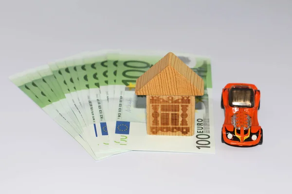 Money on a white background, next to a car and a house. Take the money in the bank. Investing in the future.