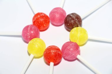 Tatlı çok renkli Carmel bir sopa. Tatlılar masaya ortaya koydu. Tatlı hayat koyu ve beyaz arka plan üzerinde. Karamel bir ve çok şeker bir daire içinde koyulur.