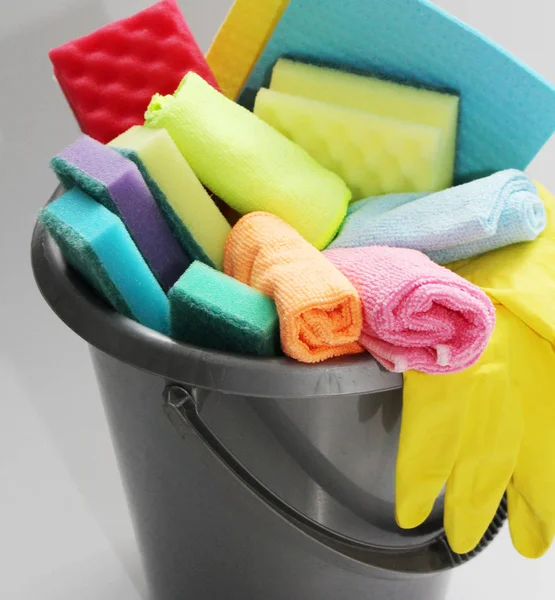 Bucket with tools for cleaning an apartment or office. No one in the photo. In the bucket are latex gloves, sponges for cleaning, detergent, floor cloth.
