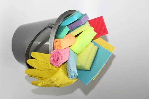 Bucket with tools for cleaning an apartment or office. No one in the photo. In the bucket are latex gloves, sponges for cleaning, detergent, floor cloth.