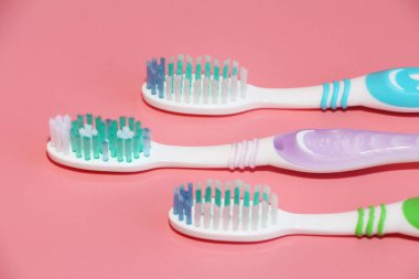 Pembe bir arka plan üzerinde üç diş fırçaları. Ağız hijyeni.