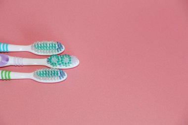 Pembe bir arka plan üzerinde üç diş fırçaları. Ağız hijyeni.