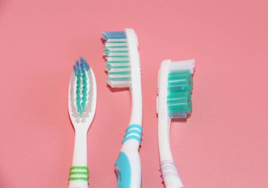 Pembe bir arka plan üzerinde üç diş fırçaları. Ağız hijyeni.