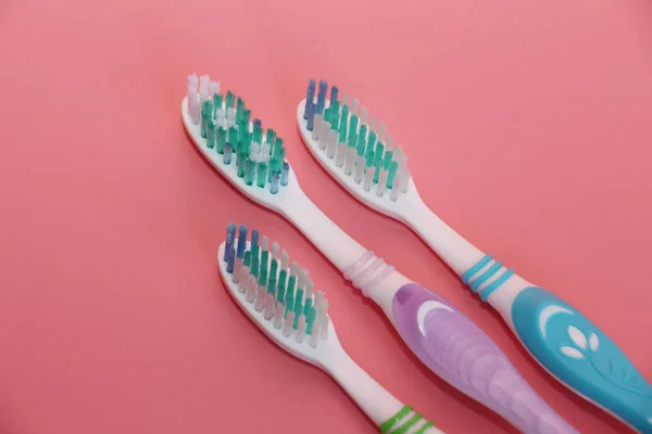 Tres cepillos de dientes sobre un fondo rosa. Higiene oral . — Foto de Stock