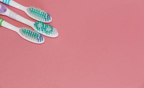 Trzy szczoteczki do zębów na różowym tle. Higiena jamy ustnej. — Zdjęcie stockowe
