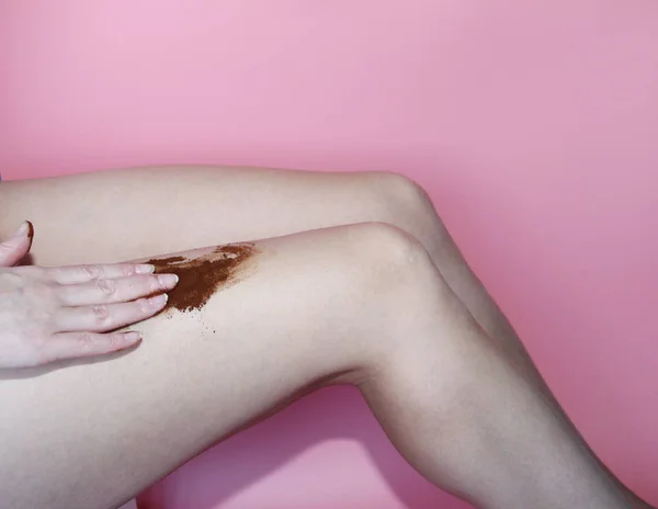 A female hand applies a scrub of ground coffee to her feet.