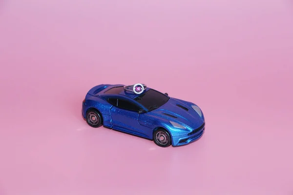 De blauwe sportwagen draagt een ring met een kristallen hart. — Stockfoto