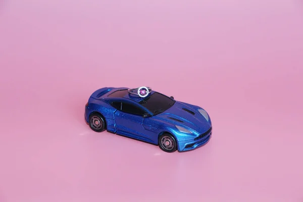 The blue sports car bears a ring with a crystal heart.