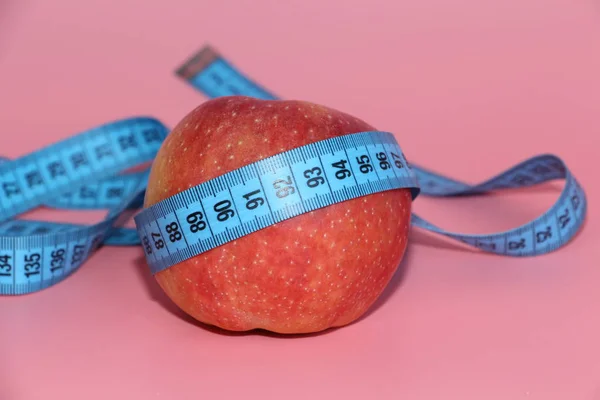 Cinta azul para medir el cuerpo alrededor de una manzana . —  Fotos de Stock