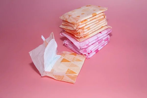 Sobre un fondo de rosa hay varias toallas sanitarias en envases individuales . — Foto de Stock