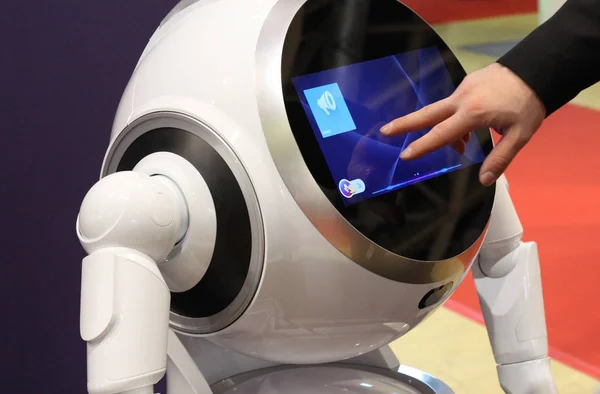 stock image Smart robot for help around the house. Male hand adjusts the settings of the robot.