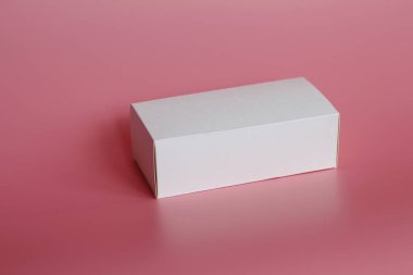 Pembe bir arka plan üzerinde beyaz kutu yatıyor. Yatay beyaz kutu.