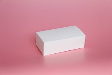 Pembe bir arka plan üzerinde beyaz kutu yatıyor. Yatay beyaz kutu.