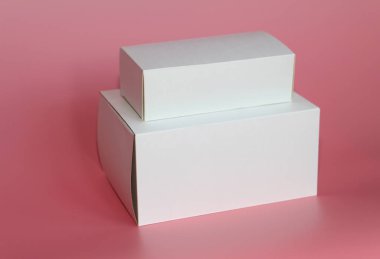 İki beyaz kutu pembe bir arka plan üzerinde. Birbirlerinin üstüne kutularıdır.