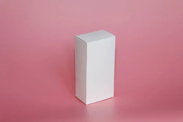 La caja blanca está sobre un fondo rosa. Caja blanca vertical . — Foto de Stock