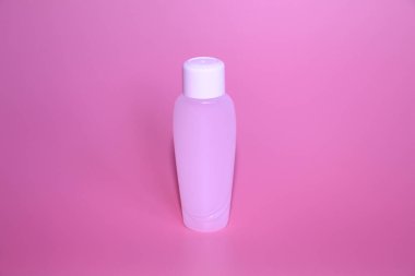 Pembe bir arka plan üzerinde bir plastik şişe. Şişe kozmetikler için.