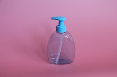 Bir mavi şişe pembe bir arka plan üzerinde. Şişe dispenseri ile kozmetikler için.