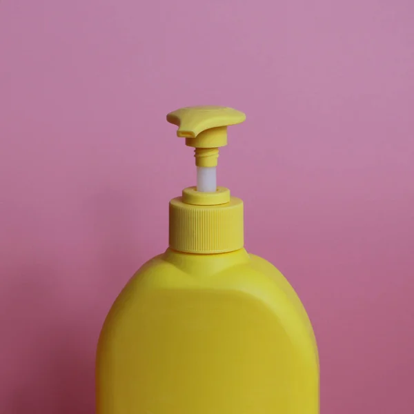 Yellow plastic bottle on a pink background. Yellow bottle with dispenser. — Stock Photo, Image