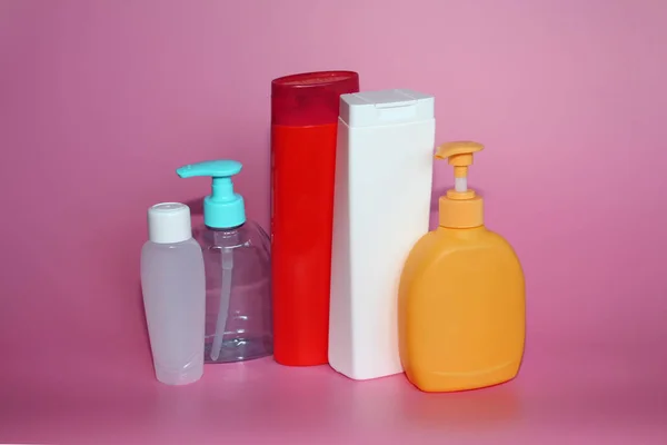 Sporo plastikowych butelek na różowym tle. Butelki do kosmetyków. — Zdjęcie stockowe