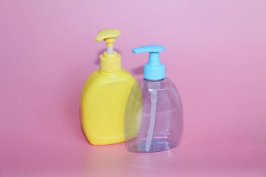 Pembe bir arka plan üzerinde iki plastik şişe. Dağıtıcı ile Kozmetik Şişeler.