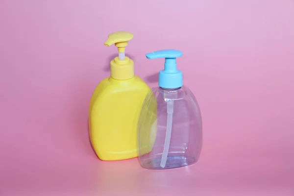 Dos botellas de plástico sobre un fondo rosa. Botellas para cosméticos con dispensador . —  Fotos de Stock