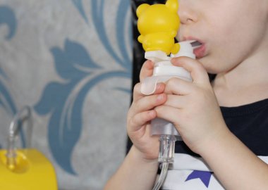Çocuk solunum yolu hastalıkları tedavisi için bir Nebulizatör elinde tutuyor. İnhalasyon.