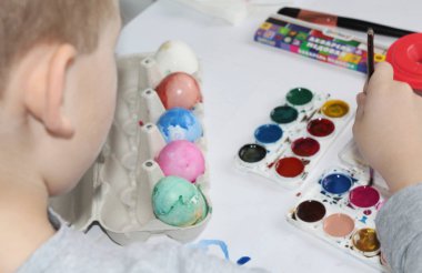 Bir çocuk yumurta fırçası ile boyar. Yumurta Paskalya için boya.