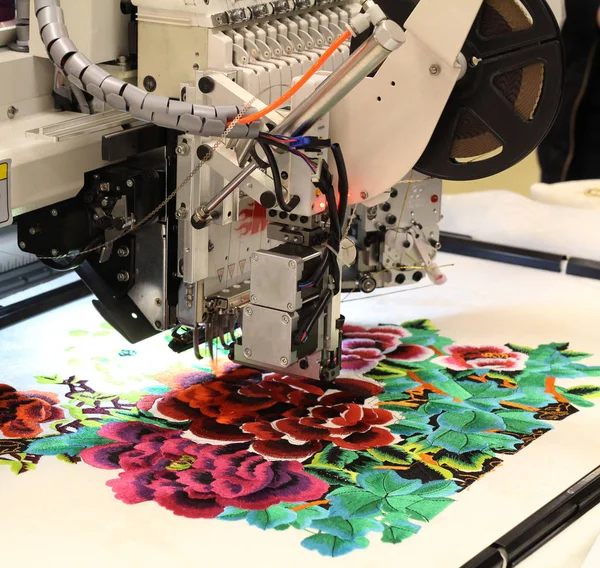 Tekstil üretimi. Makine bir çiçek desenli embroiders.