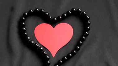 Kırmızı kalp siyah bir arka plan ve siyah inci. Siyah inci sevgiden sembolü. Arka plan - siyah saten malzeme. Kartpostal için şablon.
