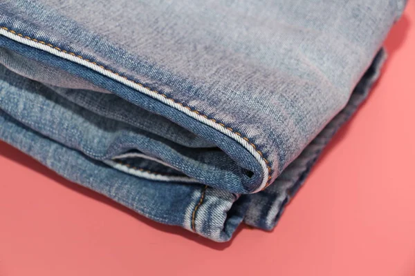 Folded blue jeans on a pink background. Faded blue jeans. — Stock Photo, Image