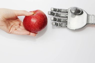 Gerçek bir adamın eli robot kırmızı bir elma verir.