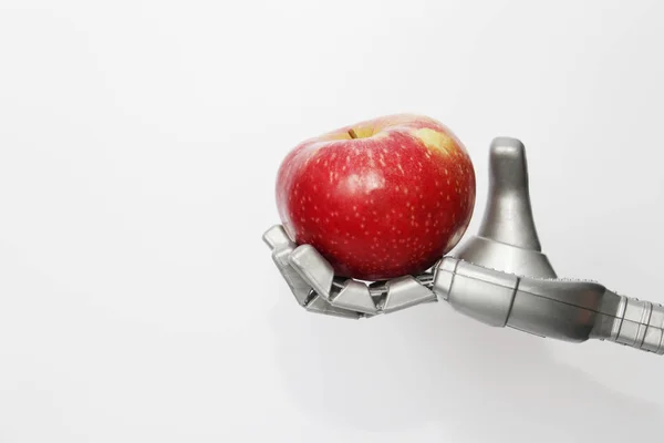 A robot hand is holding a red apple. Concept.