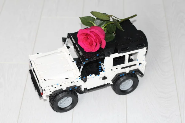 おもちゃの車のSUVは本物の赤いバラを運ぶ. — ストック写真