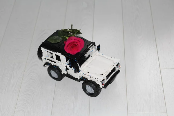 De speelgoed auto SUV draagt een echte rode roos. — Stockfoto