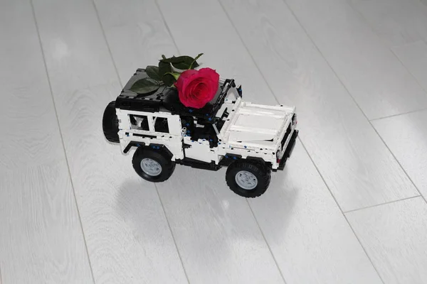 おもちゃの車のSUVは本物の赤いバラを運ぶ. — ストック写真