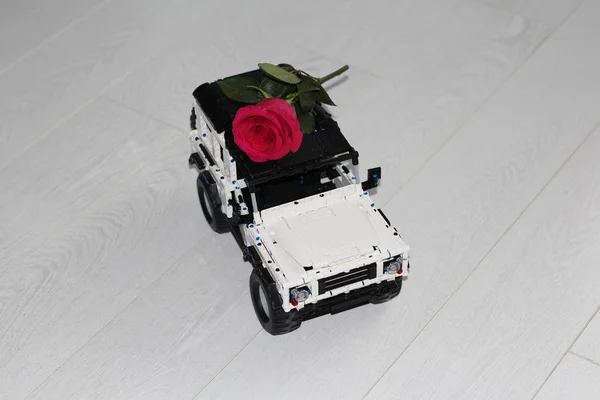 De speelgoed auto SUV draagt een echte rode roos. — Stockfoto