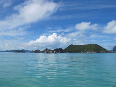 Ufukta bulutların ve turkuaz denizin birleştiği mavi gökyüzü.